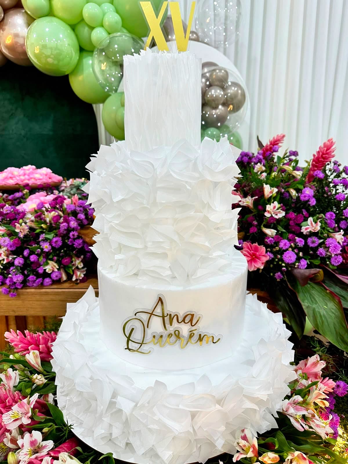 Bolo de 15 anos branco, cercado de arranjos de flores